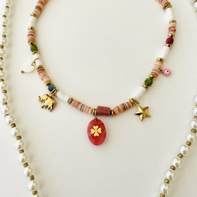 Colar com contas rosa e brancas, pendentes dourados e vermelho sobre fundo branco