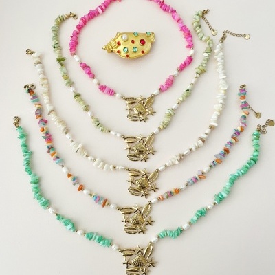 Pulseiras coloridas com pingentes de pássaro e anel dourado com pedras coloridas