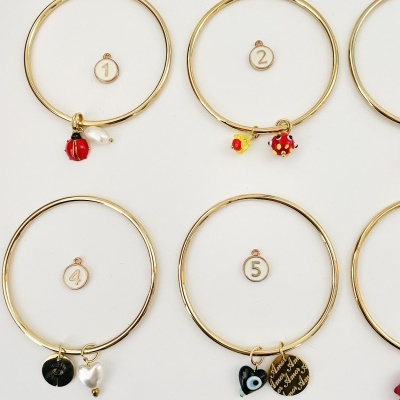 Pulseiras douradas com pendentes e números sobre fundo branco