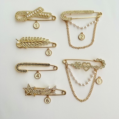Seis alfinetes de pino decorativos dourados com pérolas e brilhantes, numerados de 1 a 6.