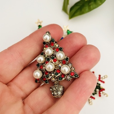Broche de árvore de Natal com pérolas e pedras coloridas, segurado na mão