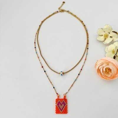 Colar duplo dourado com contas multicoloridas e pendente de contas laranja com coração roxo e dourado, flores artificiais ao lado