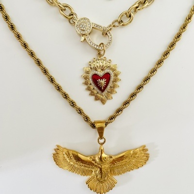 Dois colares dourados com pingentes distintos sobre fundo branco