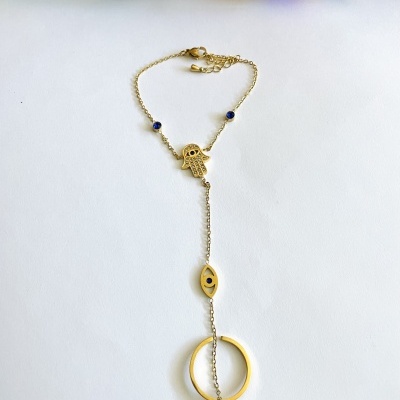 Pulseira dourada com pingentes Hamsá, olho e círculo em fundo branco com flores