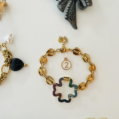 Pulseira dourada com pendente colorido e broche laço preto