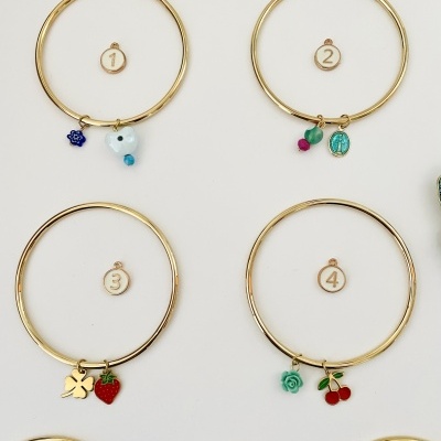 Pulseiras douradas com pendentes coloridos em fundo branco