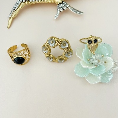 Três broches decorativos variados sobre fundo bege claro.