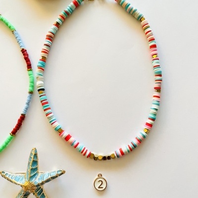 Colar colorido com pendente número 2 em fundo branco com concha e estrela-do-mar decorativa