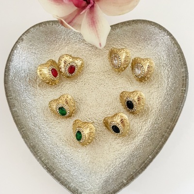 Conjunto de anéis dourados com pedras coloridas em bandeja prateada e orquídea