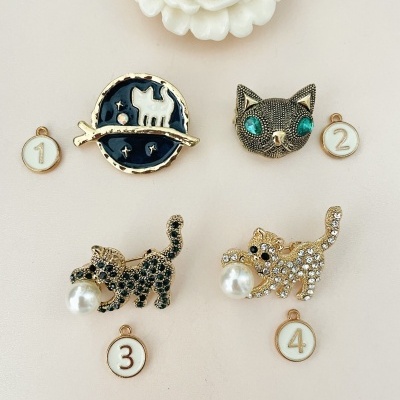 Cinco pins decorativos de gatos em metal e pérolas sobre fundo claro