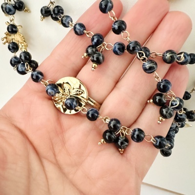 Colar com contas pretas e cinzentas e fecho dourado decorativo na mão