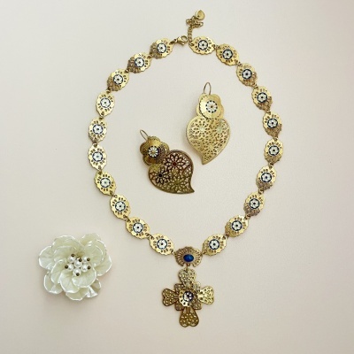 Conjunto de bijuterias douradas com colar, brincos e flor decorativa branca