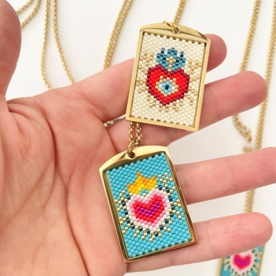 Colar com pendente retangular dourado bordado com miçangas coloridas formando corações