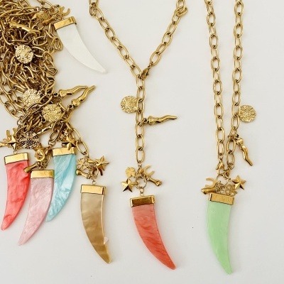 Colares com pendentes coloridos em forma de dente, detalhes dourados, estrelas e silhuetas em fundo branco.