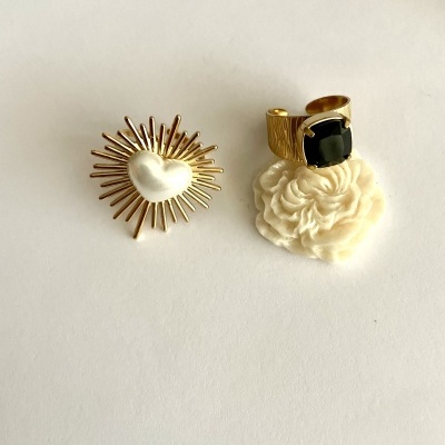 Anéis dourados com coração branco e pedra negra sobre fundo branco