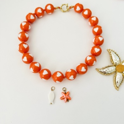 Colar com contas laranja e corações brancos com fecho dourado