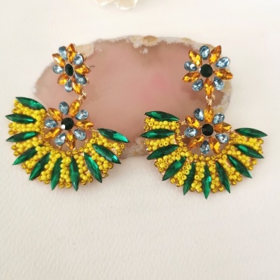 Brincos coloridos com pedras em design floral sobre fundo branco com pedra rosa e flor creme