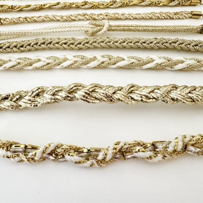 Colares dourados e brancos entrelaçados sobre fundo branco