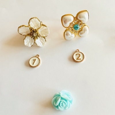 Dois anéis florais dourados, discos numerados e flor azul clara em fundo branco