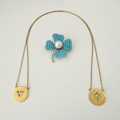 Colar dourado com pingentes religiosos e broche flor azul com pérola no centro