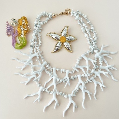 Colar branco com elementos de coral e pendente estrela do mar, mais broche de sereia colorido.