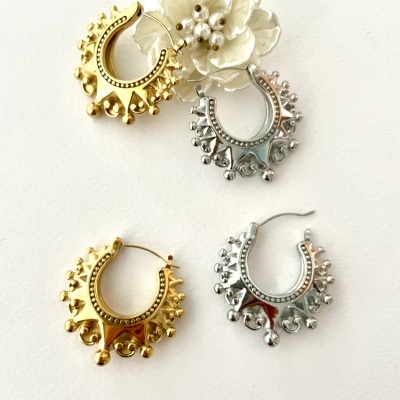 Brincos de argola dourados e prateados com decoração esférica em fundo branco com flor decorativa creme