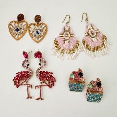 Quatro pares de brincos decorativos sobre fundo branco