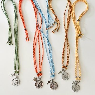 Cinco colares trançados coloridos com pendentes redondos prateados e detalhes metálicos