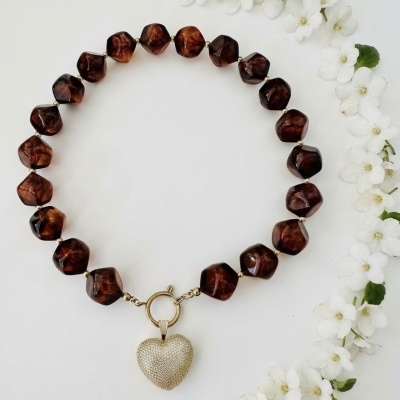 Colar de contas marrons com pingente de coração dourado e flores brancas