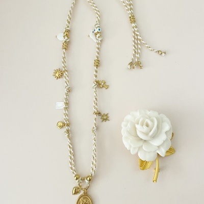 Colar trançado com pendentes dourados e broche branco em forma de flor
