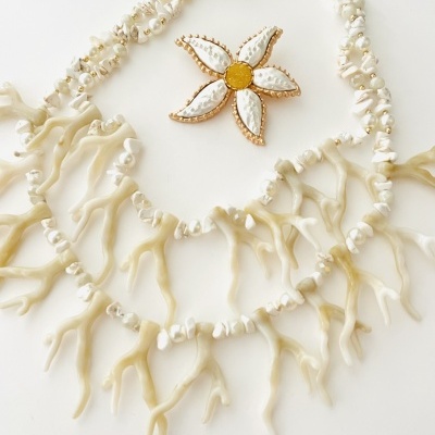 Colar e broche decorativos com elementos em forma de coral e flor em branco e dourado