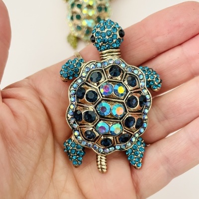 Broche ou pendente em forma de tartaruga com cristais azuis e multicoloridos na mão