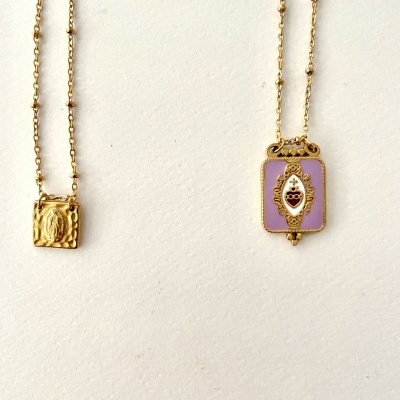 Dois colares dourados com pendentes detalhados em fundo branco