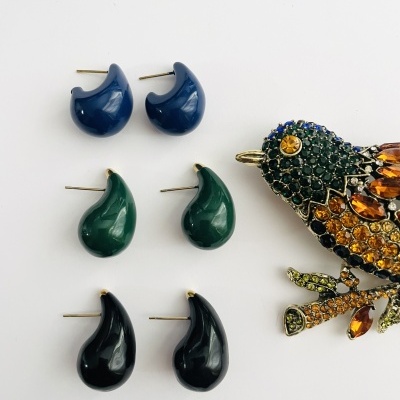 Três pares de brincos coloridos e broche de pássaro com pedras brilhantes