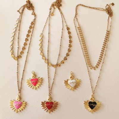 Colares dourados com pendentes de coração coloridos em rosa, vermelho, branco e preto sobre fundo claro