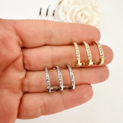 Conjunto de seis anéis dourados e prateados com cristais numa mão