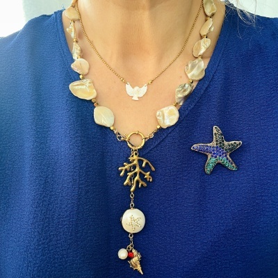 Colares e broche com pedras naturais e pendentes dourados em tecido azul.