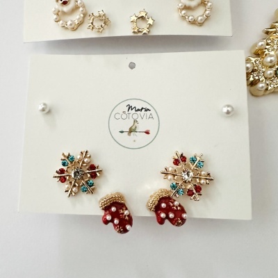 Conjunto de brincos natalícios com flocos de neve e luvas vermelhas em cartão de marca.