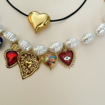Colar com contas brancas e vários pendentes em forma de coração e um colar com pendente de coração dourado e fio preto