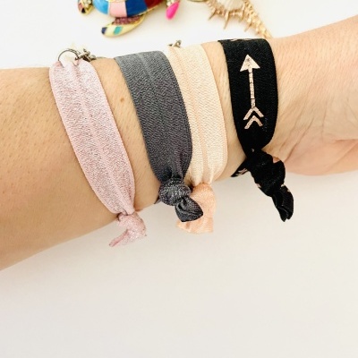 Pulseiras de tecido coloridas num pulso com fundo branco e objetos decorativos coloridos