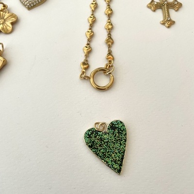 Pendentes dourados variados com um pendente de coração verde brilhante