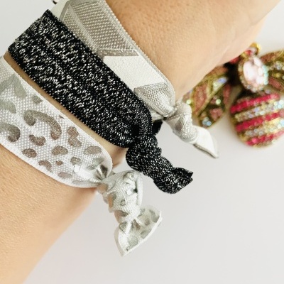 Braceletes elásticos em tecido com padrões e cores variadas no pulso de uma pessoa