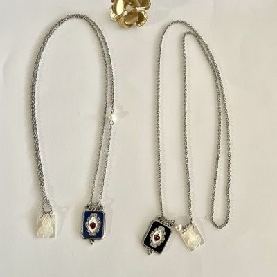 Dois colares prateados com pendentes retangulares coloridos e um anel dourado em fundo branco