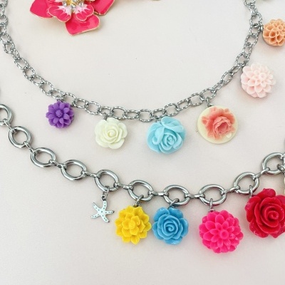 Duas pulseiras prateadas com pendentes de flores coloridas e uma estrela do mar