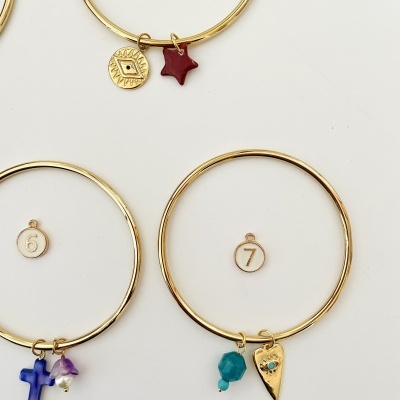 Conjunto de pulseiras douradas com pendentes coloridos e medalhas numeradas