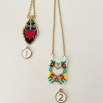 Dois colares com pendentes de miçangas coloridas e etiquetas numeradas, sobre fundo claro.