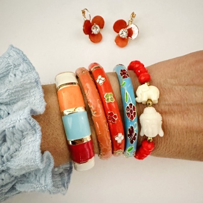 Pulseiras coloridas em esmalte e contas com padrões florais e figuras, e brincos vermelhos em forma de flor com pedra central.
