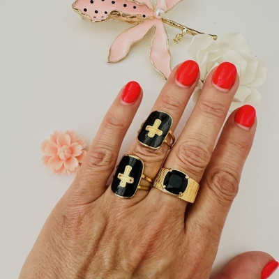 Mão com três anéis dourados e unhas vermelhas sobre fundo com flores