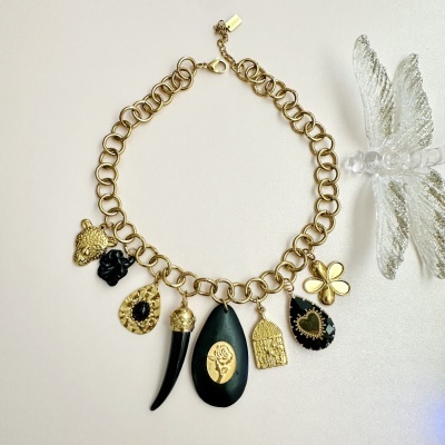 Colar dourado com vários pendentes variados e figura de libélula transparente ao lado