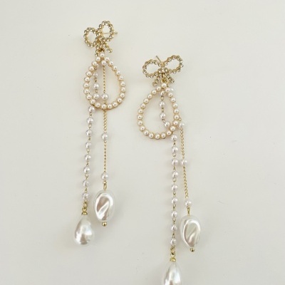 brincos pendentes dourados com pérolas e gotas maiores em fundo branco